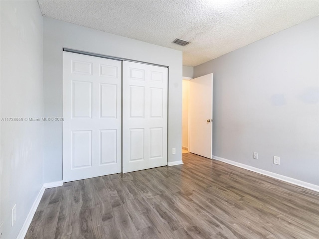 unfurnished bedroom featuring wood-type flooring, a textured ceiling, and a closet