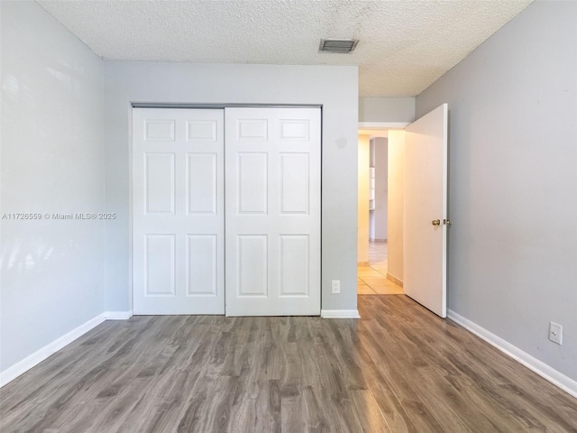 unfurnished bedroom with dark hardwood / wood-style flooring, a closet, and a textured ceiling