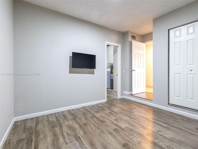 unfurnished bedroom with hardwood / wood-style flooring, a textured ceiling, and a closet