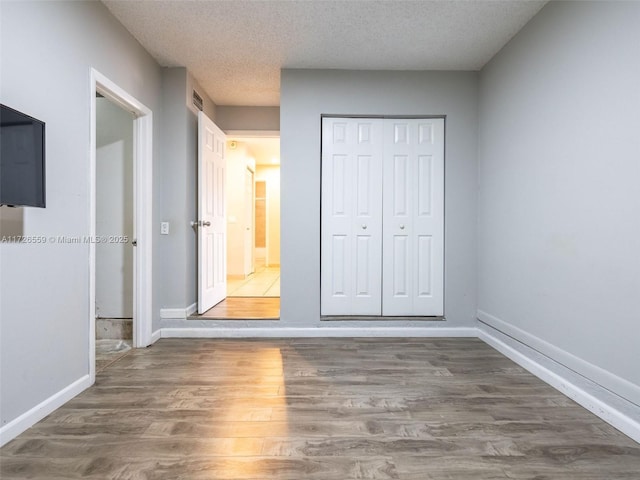 unfurnished bedroom featuring a closet, dark hardwood / wood-style floors, and a textured ceiling