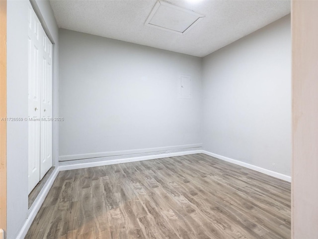 spare room featuring a textured ceiling and light hardwood / wood-style floors