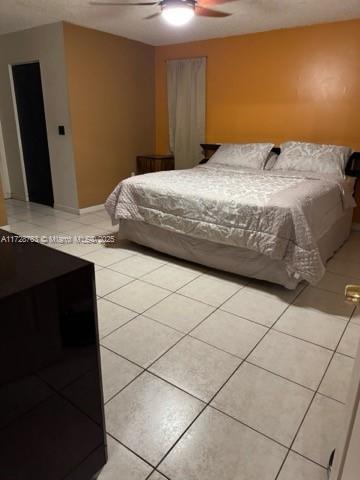 tiled bedroom featuring ceiling fan