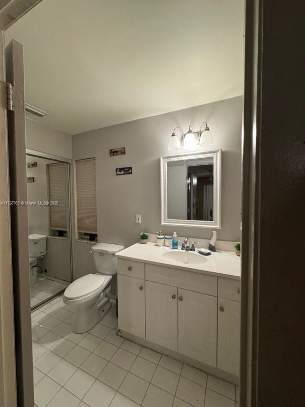 bathroom with toilet, vanity, and tile patterned floors