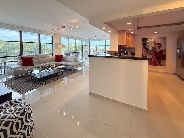 kitchen featuring track lighting, sink, kitchen peninsula, floor to ceiling windows, and light tile patterned floors