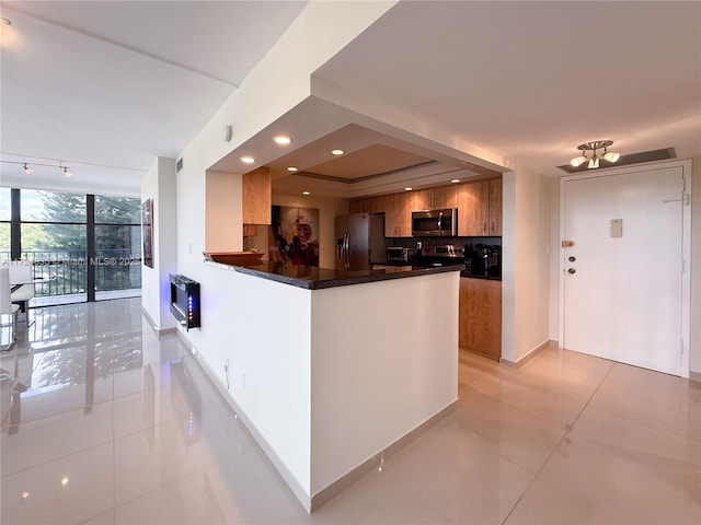 kitchen featuring appliances with stainless steel finishes, backsplash, kitchen peninsula, light tile patterned flooring, and floor to ceiling windows