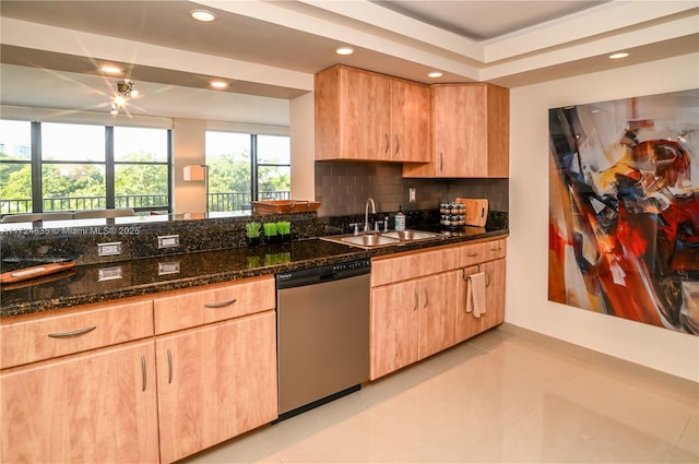 kitchen featuring dishwasher, dark stone countertops, light brown cabinetry, sink, and backsplash