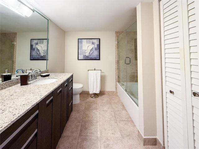 full bathroom featuring toilet, vanity, tile patterned flooring, and combined bath / shower with glass door