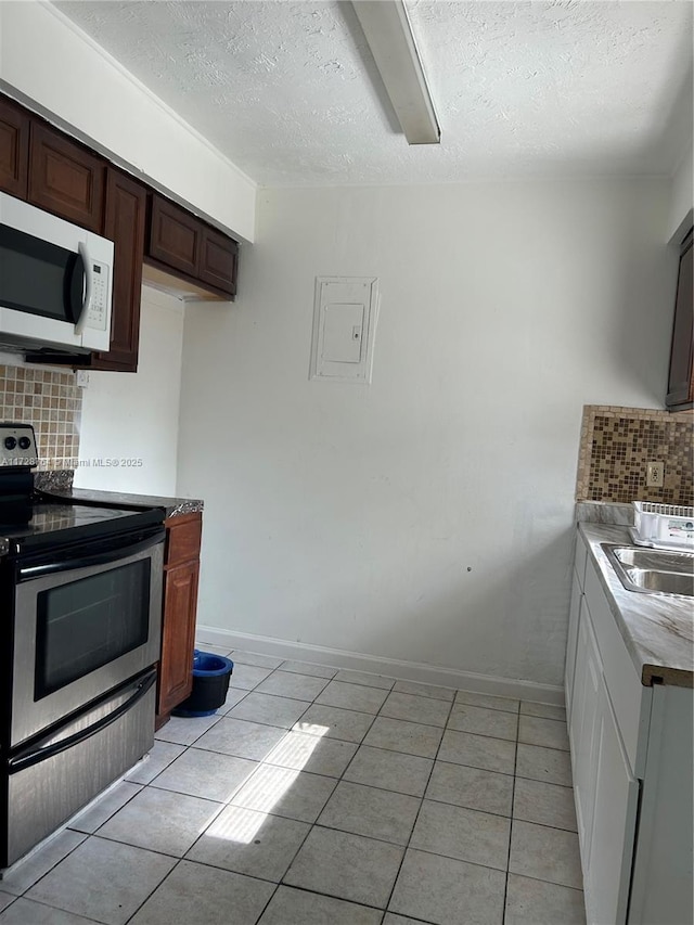 kitchen featuring a textured ceiling, tasteful backsplash, light tile patterned flooring, dark brown cabinets, and stainless steel electric range