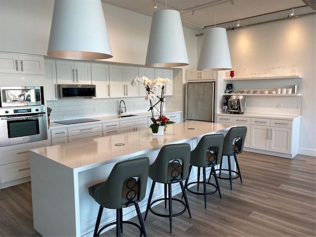 kitchen with decorative light fixtures, decorative backsplash, white cabinets, and built in appliances