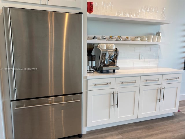 bar with hardwood / wood-style flooring, white cabinets, and stainless steel fridge