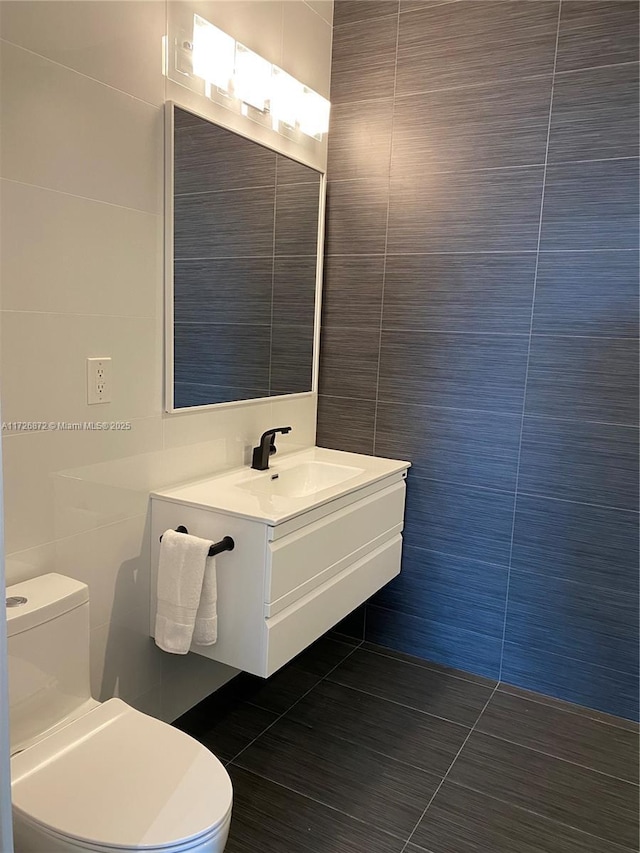 bathroom featuring toilet, vanity, tile walls, and tile patterned flooring