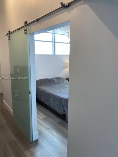 bedroom with a barn door and hardwood / wood-style floors