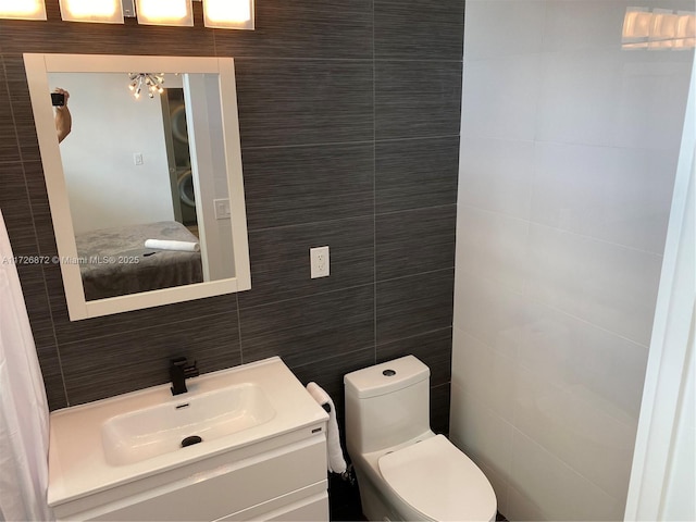 bathroom with tile walls, toilet, vanity, and tasteful backsplash