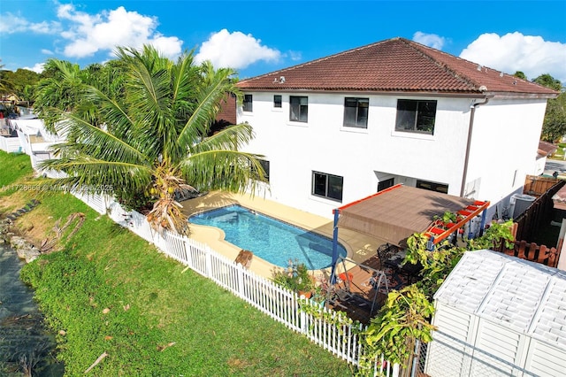 rear view of property with a fenced in pool, a yard, and a patio