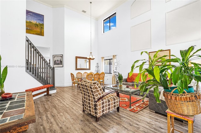 living room featuring a high ceiling, an inviting chandelier, ornamental molding, and hardwood / wood-style flooring