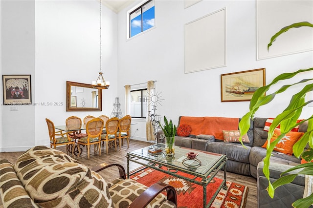 living room with a chandelier, a towering ceiling, and wood-type flooring