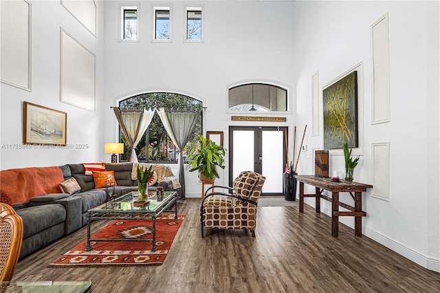 living room featuring dark hardwood / wood-style flooring, a towering ceiling, and french doors