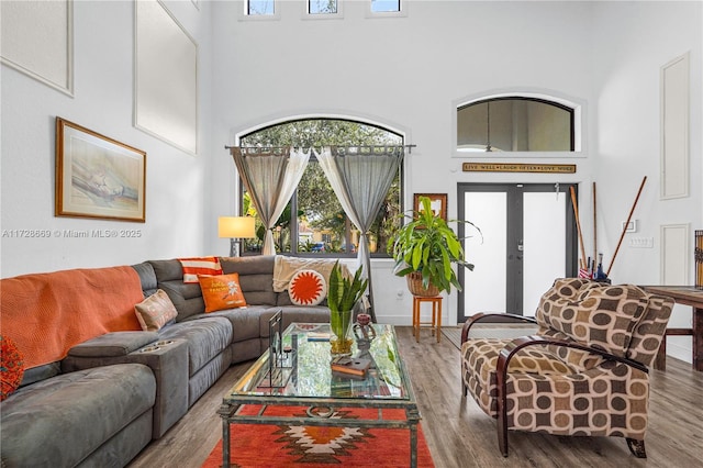 living room featuring french doors, hardwood / wood-style floors, and a towering ceiling