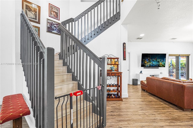 staircase with wood-type flooring, french doors, and a textured ceiling