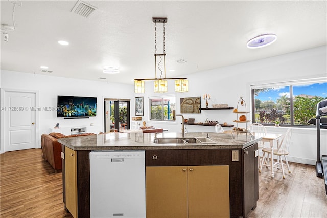 kitchen with decorative light fixtures, light hardwood / wood-style floors, sink, white dishwasher, and a center island with sink