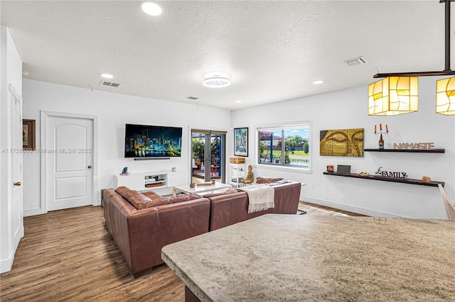 living room with a textured ceiling, hardwood / wood-style flooring, and french doors