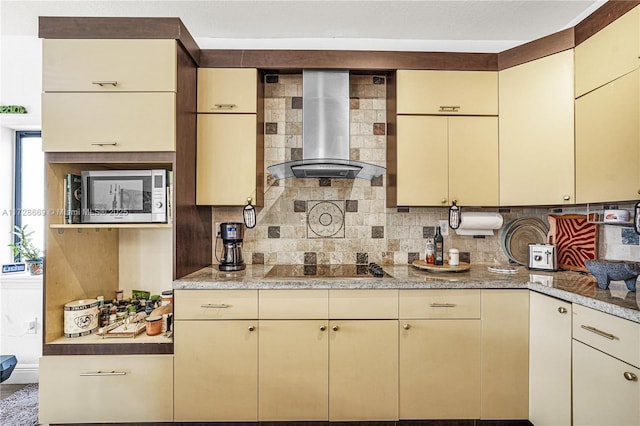 kitchen with decorative backsplash, cream cabinetry, and wall chimney range hood