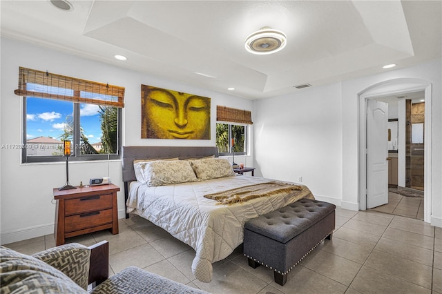 bedroom with tile patterned flooring and a tray ceiling