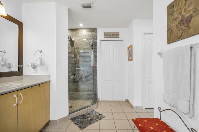 bathroom featuring a shower with shower door, vanity, and tile patterned floors