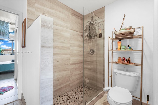 bathroom featuring a shower with shower door and toilet