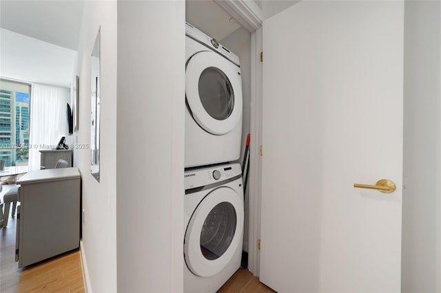 laundry room with stacked washer / drying machine and light hardwood / wood-style floors