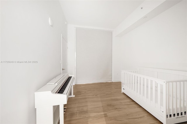 unfurnished bedroom featuring light hardwood / wood-style floors and a nursery area