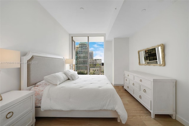 bedroom with floor to ceiling windows and light hardwood / wood-style flooring