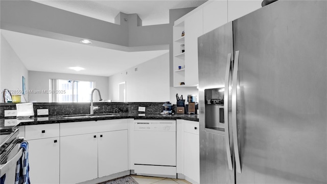 kitchen with sink, white cabinets, stainless steel appliances, and dark stone counters