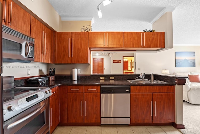 kitchen with appliances with stainless steel finishes, ornamental molding, a peninsula, and a sink