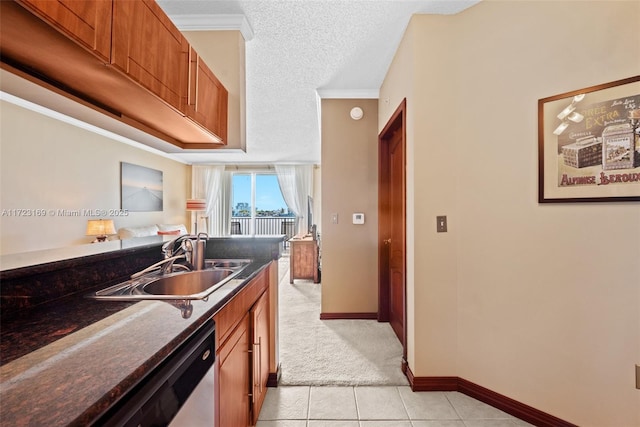 kitchen featuring a textured ceiling, dark stone counters, a sink, dishwasher, and brown cabinetry