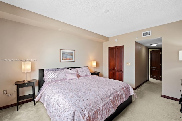 bedroom with a closet, visible vents, light carpet, a textured ceiling, and baseboards