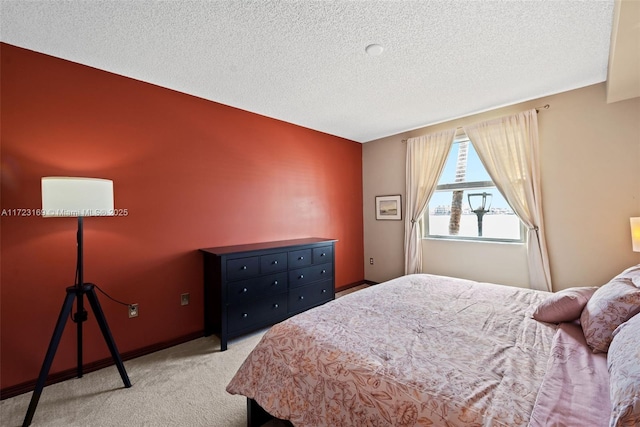 bedroom featuring light colored carpet, a textured ceiling, and baseboards