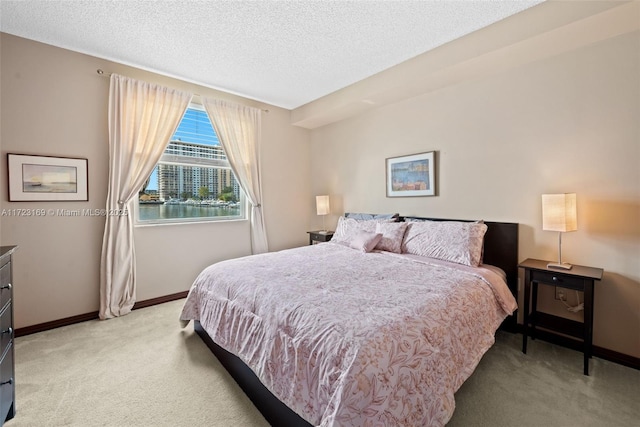 bedroom with baseboards, a textured ceiling, and light colored carpet