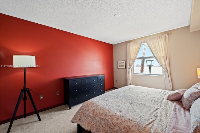 bedroom with light carpet, a textured ceiling, and baseboards