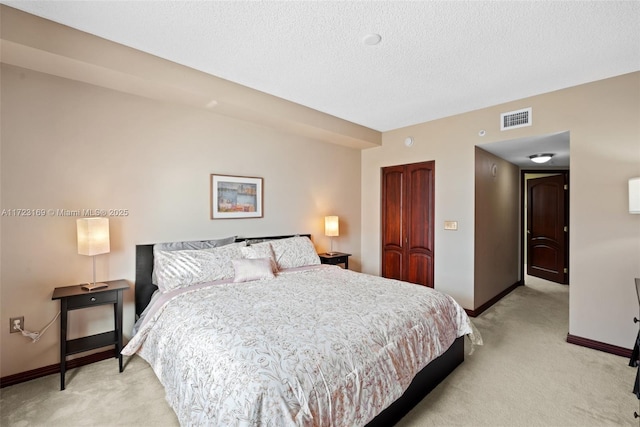 bedroom with baseboards, visible vents, light colored carpet, a textured ceiling, and a closet