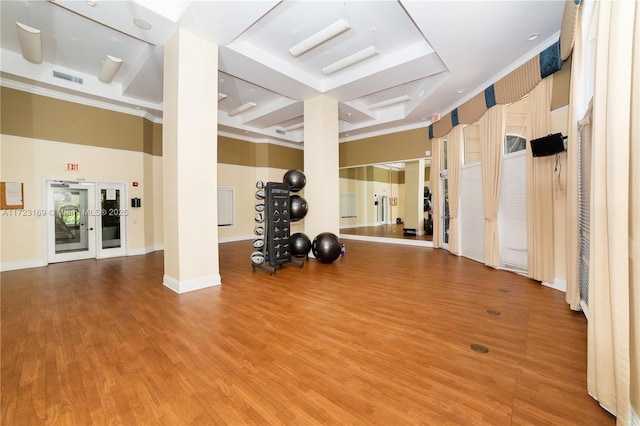 exercise room with wood finished floors, visible vents, and baseboards