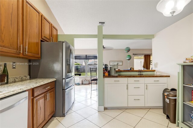 kitchen with light stone counters, light tile patterned floors, and white appliances