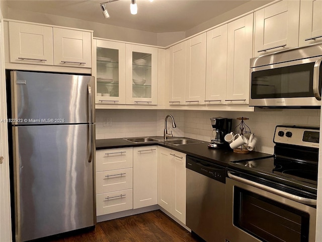 kitchen with backsplash, sink, white cabinetry, dark wood-type flooring, and appliances with stainless steel finishes