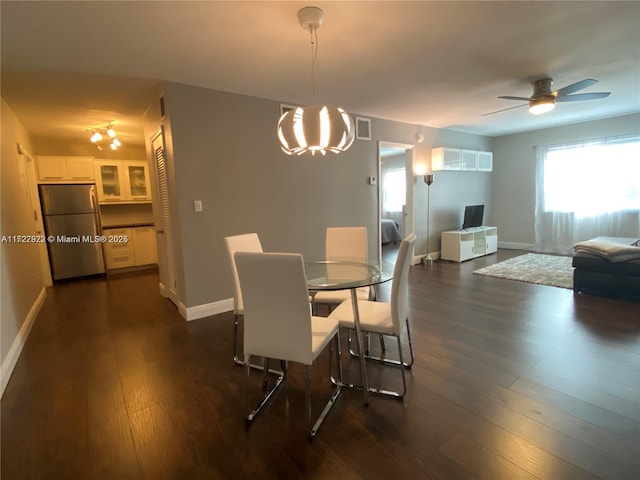 dining area with ceiling fan with notable chandelier and dark hardwood / wood-style floors