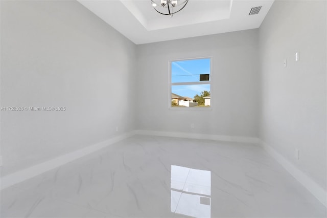 unfurnished room with a raised ceiling and a chandelier