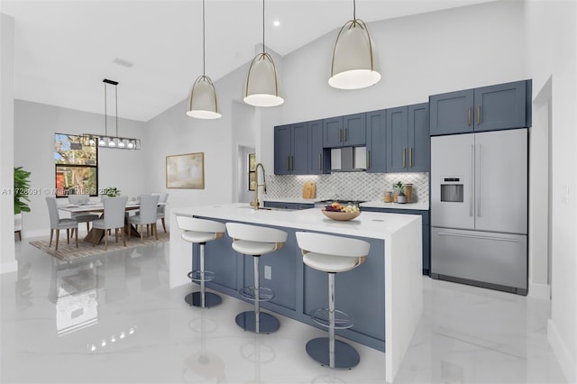 kitchen with stainless steel built in refrigerator, a breakfast bar area, backsplash, and decorative light fixtures