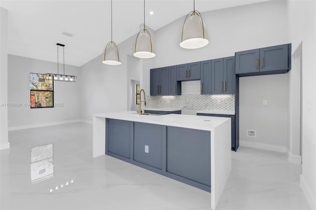 kitchen with backsplash, sink, hanging light fixtures, and a center island with sink