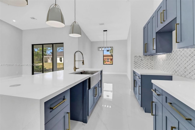 kitchen featuring blue cabinetry, sink, a center island with sink, pendant lighting, and decorative backsplash