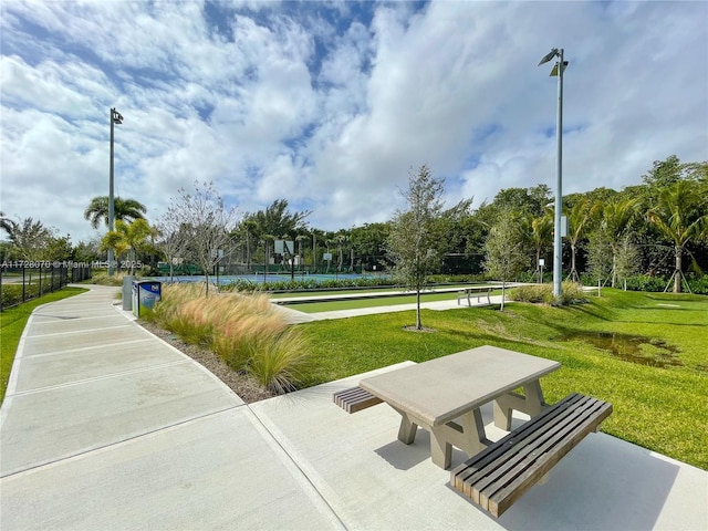 view of property's community featuring tennis court and a yard