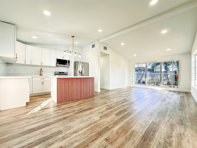 kitchen featuring stainless steel appliances, a center island, vaulted ceiling with beams, and pendant lighting